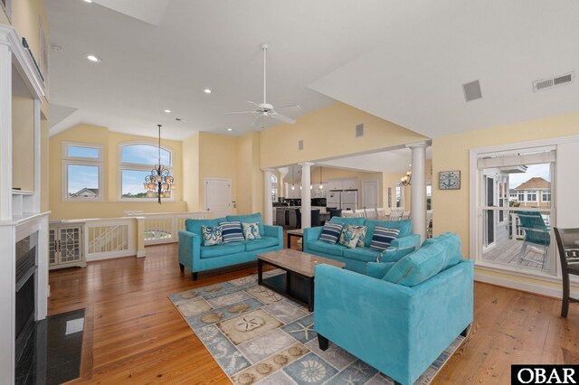 living room featuring recessed lighting, wood finished floors, visible vents, vaulted ceiling, and ornate columns