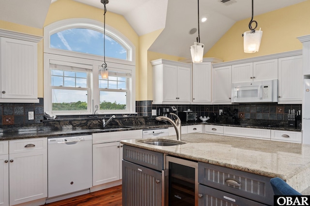 kitchen featuring decorative light fixtures, white cabinets, beverage cooler, light stone countertops, and white appliances