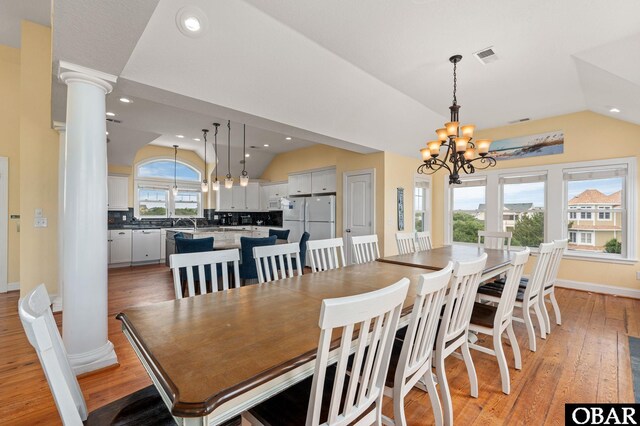 dining area with lofted ceiling, recessed lighting, light wood-style flooring, a chandelier, and ornate columns