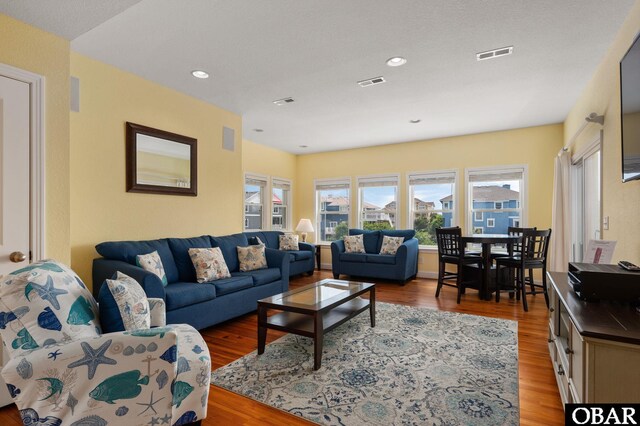 living room with recessed lighting, visible vents, and wood finished floors