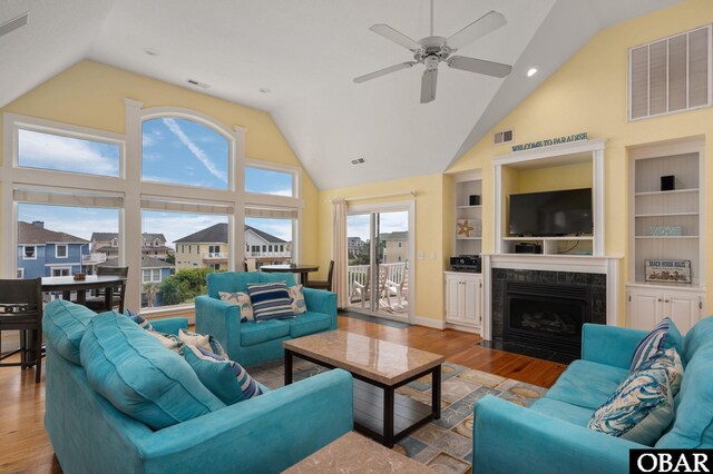 living room with light wood-style flooring, built in shelves, visible vents, and a premium fireplace