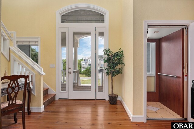 foyer entrance featuring stairs, wood finished floors, and baseboards