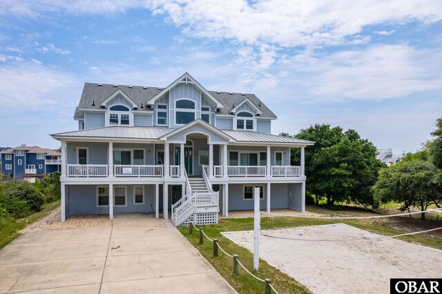 beach home featuring metal roof, covered porch, stairs, driveway, and a standing seam roof