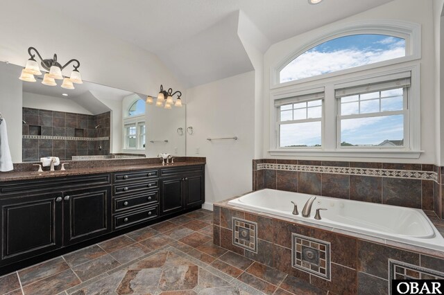 bathroom featuring vaulted ceiling, a sink, a bath, and double vanity