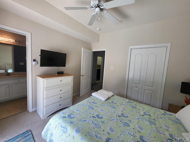 bedroom featuring light colored carpet, a sink, a ceiling fan, a closet, and ensuite bath