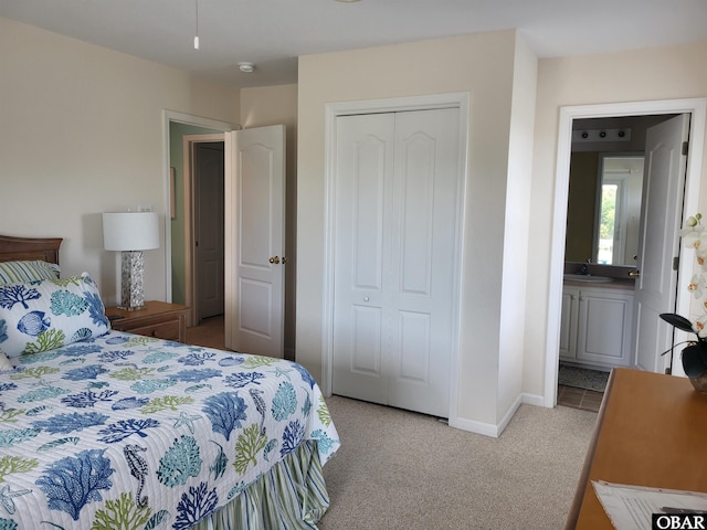 bedroom featuring a sink, light carpet, a closet, and baseboards