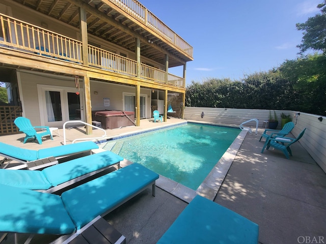 view of pool featuring a patio area, fence, a fenced in pool, and a hot tub