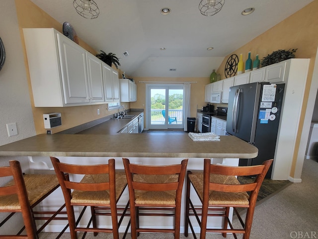 kitchen with freestanding refrigerator, white cabinets, double oven range, a peninsula, and a kitchen bar