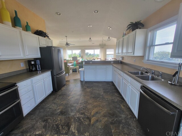 kitchen featuring white cabinets, a peninsula, stainless steel appliances, and a sink