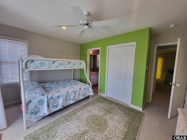 carpeted bedroom featuring connected bathroom, baseboards, a closet, and a ceiling fan