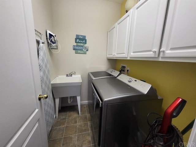 laundry area with dark tile patterned flooring, washing machine and clothes dryer, cabinet space, and baseboards