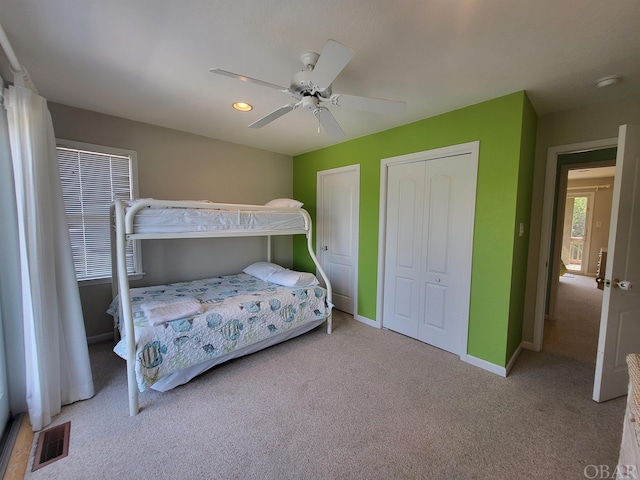 bedroom with baseboards, ceiling fan, visible vents, and light colored carpet