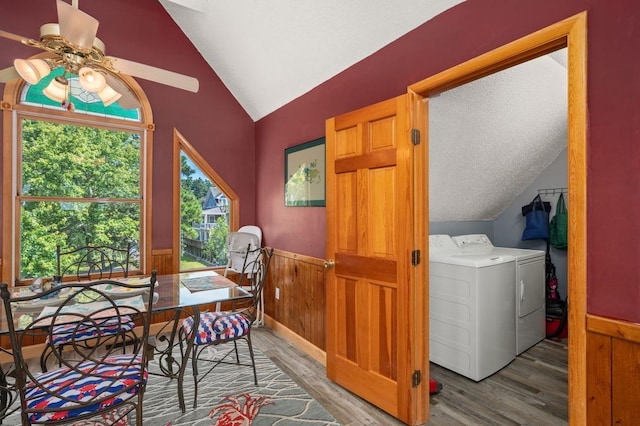 dining room featuring lofted ceiling, wainscoting, washing machine and clothes dryer, and wood finished floors