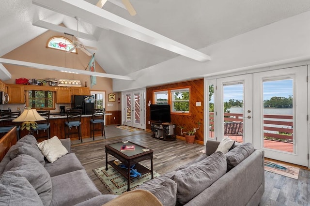 living area featuring french doors, beam ceiling, wood walls, wood finished floors, and high vaulted ceiling