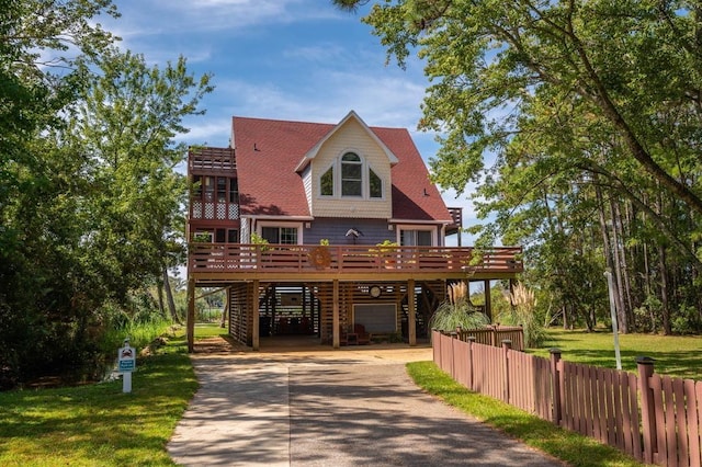 raised beach house with a garage, fence, stairs, concrete driveway, and a wooden deck