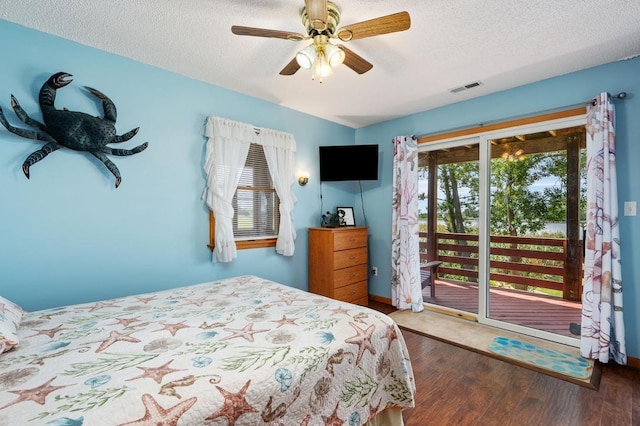 bedroom featuring a textured ceiling, access to outside, wood finished floors, and visible vents