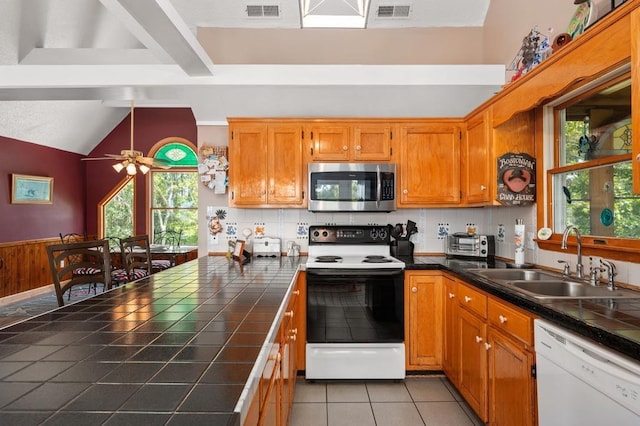 kitchen with tile countertops, electric range oven, a sink, dishwasher, and stainless steel microwave