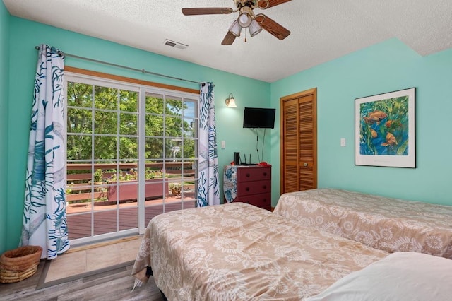 bedroom featuring a closet, visible vents, a textured ceiling, wood finished floors, and access to outside