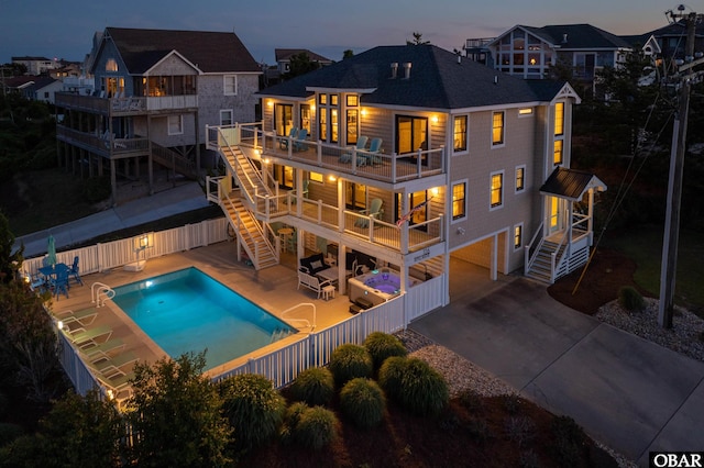 126 Buffell Head Rd Lot 146, Duck, NC 27949 - back of house at dusk with stairway, a fenced backyard, an attached garage, and a balcony