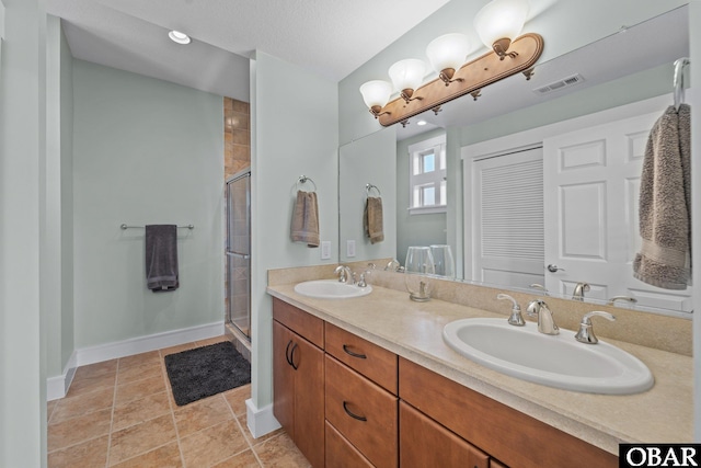 bathroom featuring baseboards, a sink, visible vents, and a shower stall