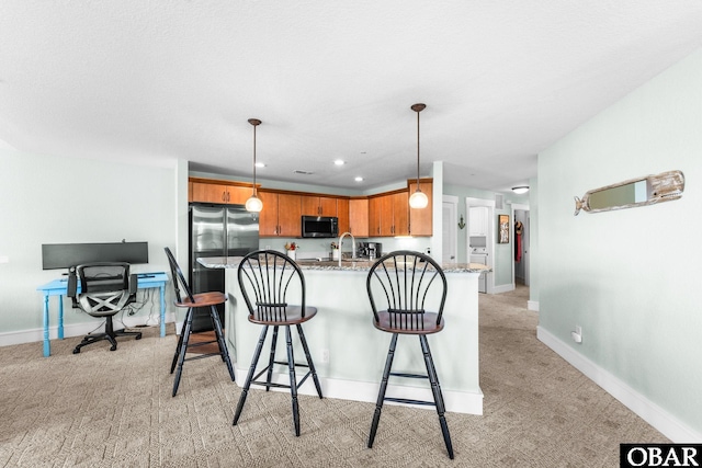 kitchen featuring hanging light fixtures, light carpet, light stone counters, and freestanding refrigerator