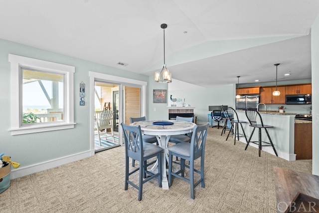 dining room with lofted ceiling, baseboards, visible vents, and light colored carpet