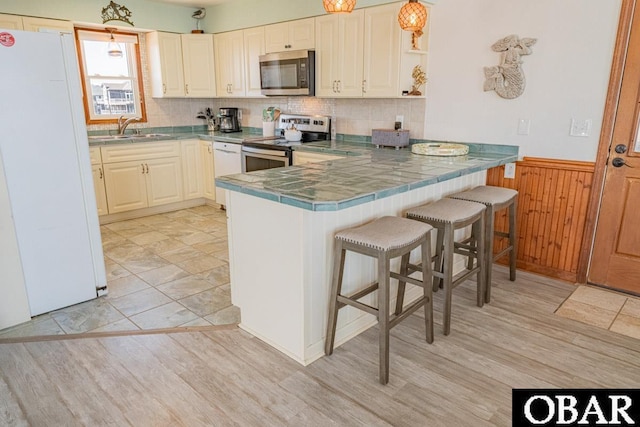 24143 Ocean Dr Lot 4, Rodanthe, NC 27968 - kitchen with appliances with stainless steel finishes, a sink, a peninsula, open shelves, and a kitchen breakfast bar