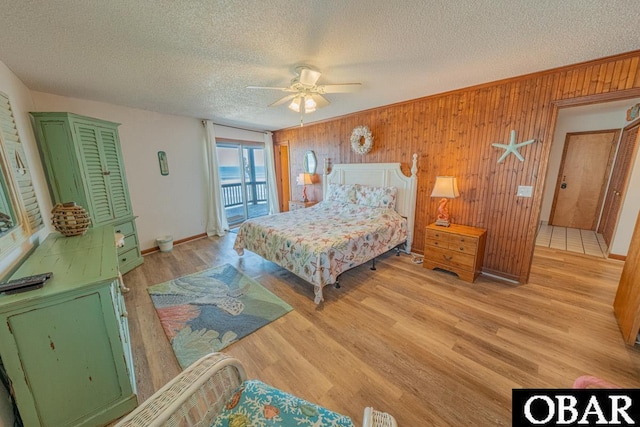 24143 Ocean Dr Lot 4, Rodanthe, NC 27968 - bedroom with access to outside, a textured ceiling, wooden walls, light wood-type flooring, and ceiling fan