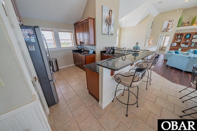 22097 Sea Gull St Lot 7, Rodanthe, NC 27968 - kitchen featuring a breakfast bar area, a peninsula, freestanding refrigerator, open floor plan, and dark stone counters