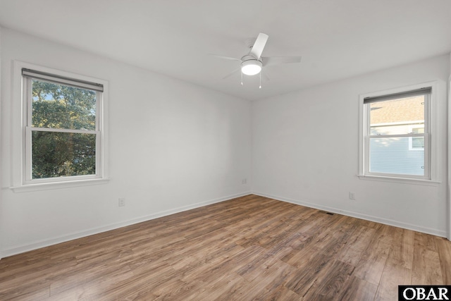 unfurnished room with ceiling fan, wood finished floors, and baseboards