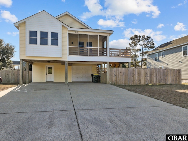 view of front of house with driveway, a sunroom, an attached garage, and a carport