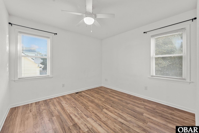 empty room with a ceiling fan, baseboards, and wood finished floors