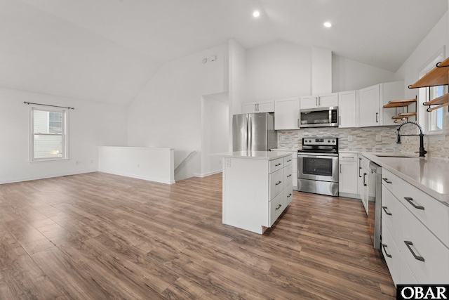 kitchen with a center island, open shelves, stainless steel appliances, light countertops, and white cabinets