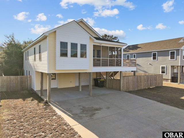 view of front of property featuring a sunroom, fence, and concrete driveway