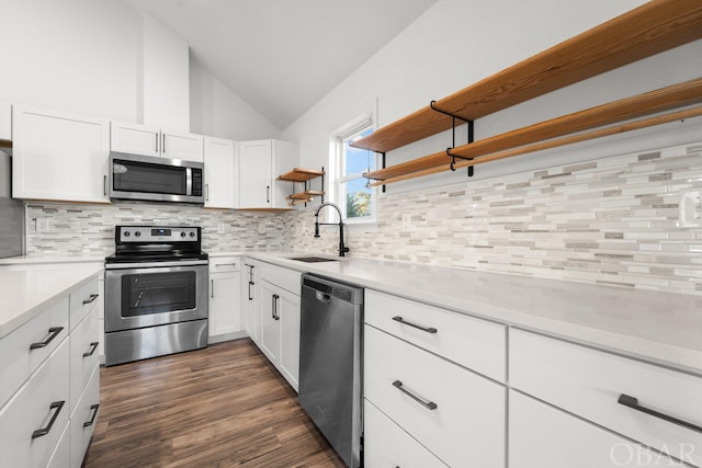 kitchen with lofted ceiling, stainless steel appliances, a sink, white cabinetry, and light countertops