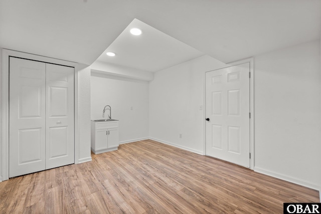 interior space featuring baseboards, light wood-style flooring, a sink, a closet, and recessed lighting