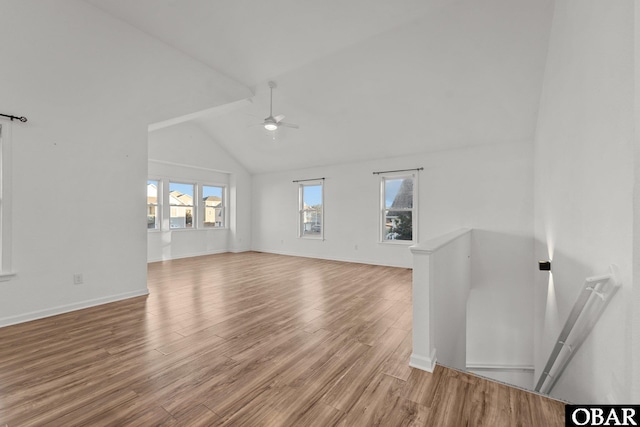 unfurnished living room featuring ceiling fan, high vaulted ceiling, light wood-type flooring, and baseboards