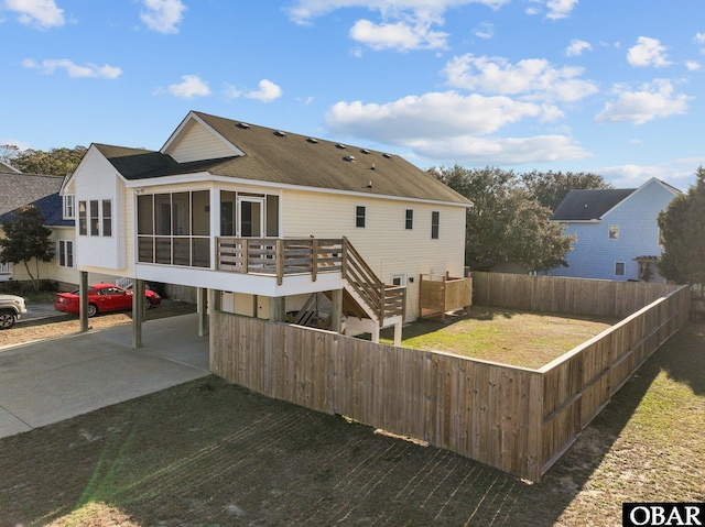 rear view of house featuring fence private yard, a shingled roof, a sunroom, stairs, and a yard