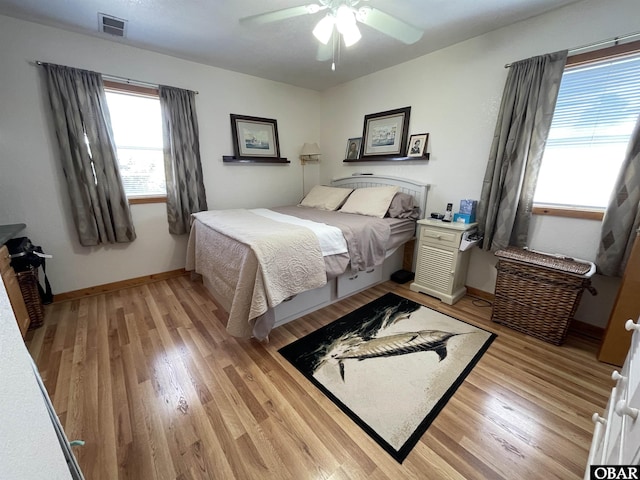 bedroom featuring light wood-style flooring, baseboards, a ceiling fan, and visible vents