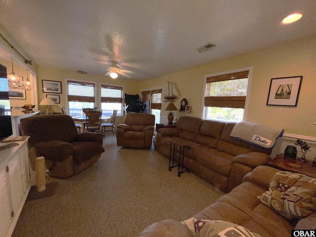 living room featuring visible vents, a ceiling fan, and a healthy amount of sunlight