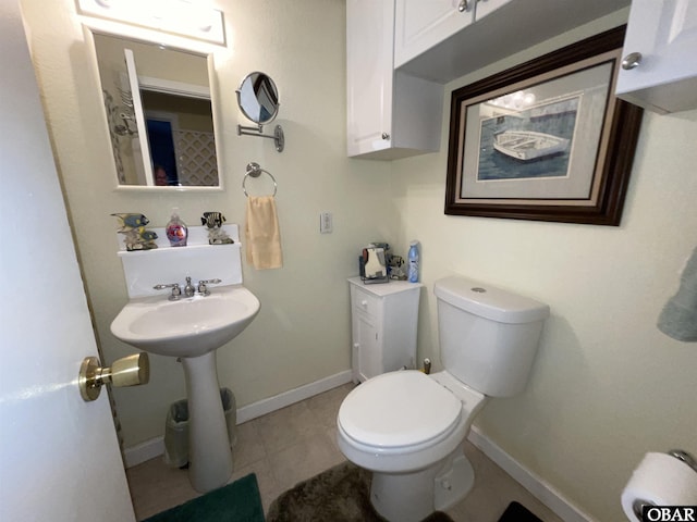 half bath featuring tile patterned floors, baseboards, and toilet