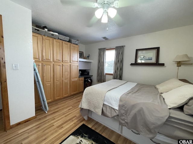 bedroom featuring light wood finished floors, visible vents, baseboards, and a ceiling fan