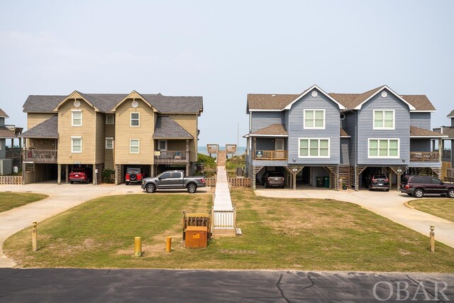 townhome / multi-family property with a shingled roof, a residential view, a front lawn, and concrete driveway