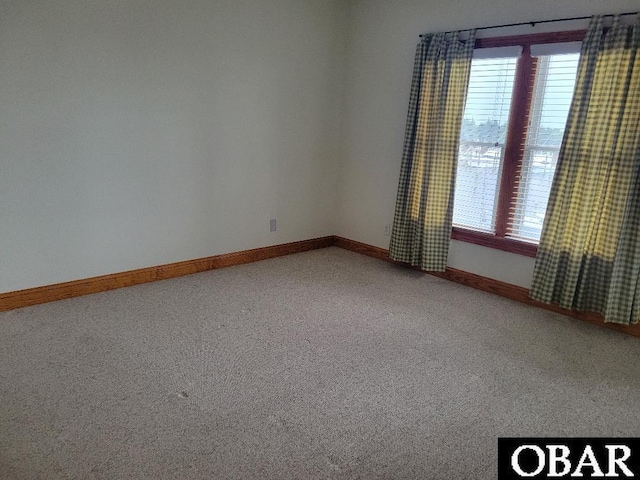 unfurnished room with carpet and baseboards