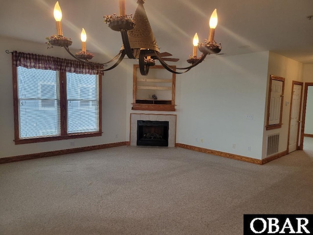 unfurnished living room with carpet flooring, a notable chandelier, baseboards, and visible vents