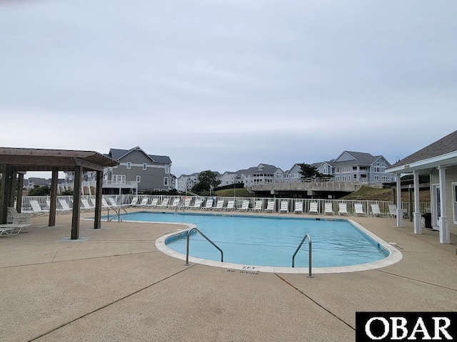 pool with fence, a patio, and a residential view