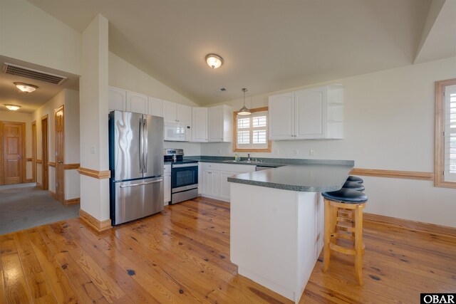 1602 Harbour View Dr Lot 119, Kill Devil Hills, NC 27948 - kitchen with stainless steel appliances, a peninsula, white cabinetry, lofted ceiling, and a kitchen breakfast bar