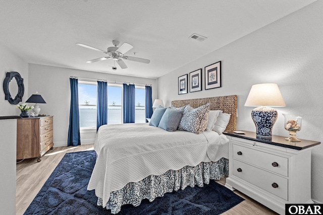 bedroom with light wood-style floors, baseboards, a ceiling fan, and visible vents
