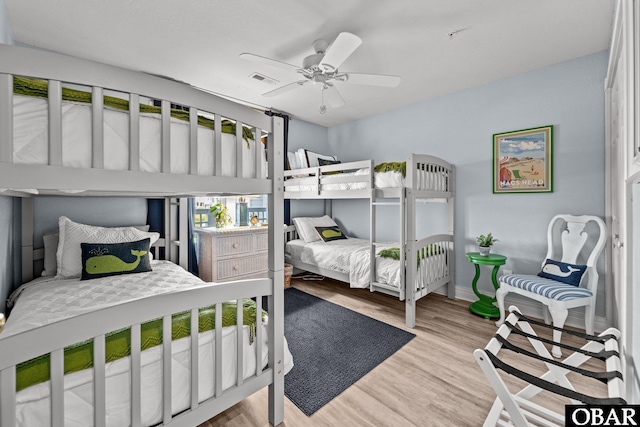 bedroom featuring baseboards, ceiling fan, wood finished floors, and visible vents