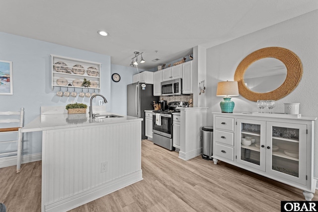 kitchen featuring light wood-style floors, a sink, white cabinetry, and stainless steel appliances